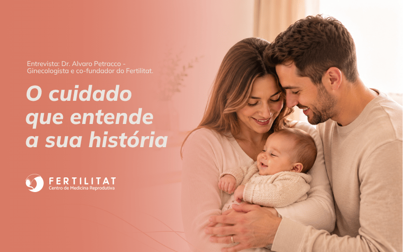 Casal sorridente segurando um bebê no colo em ambiente acolhedor, representando cuidado, acolhimento e medicina reprodutiva. A imagem promove entrevista com Dr. Álvaro Petracco, ginecologista e cofundador da Fertilitat, com o texto “O cuidado que entende a sua história”.